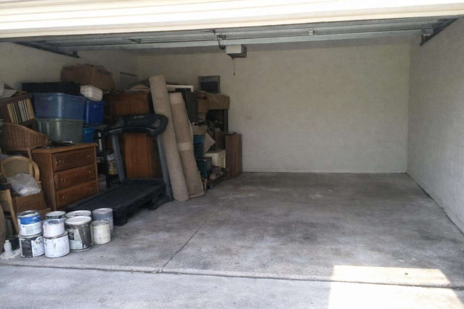 A two-car garage in Orlando with one half stacked with old furniture and bins and the other half swept clear