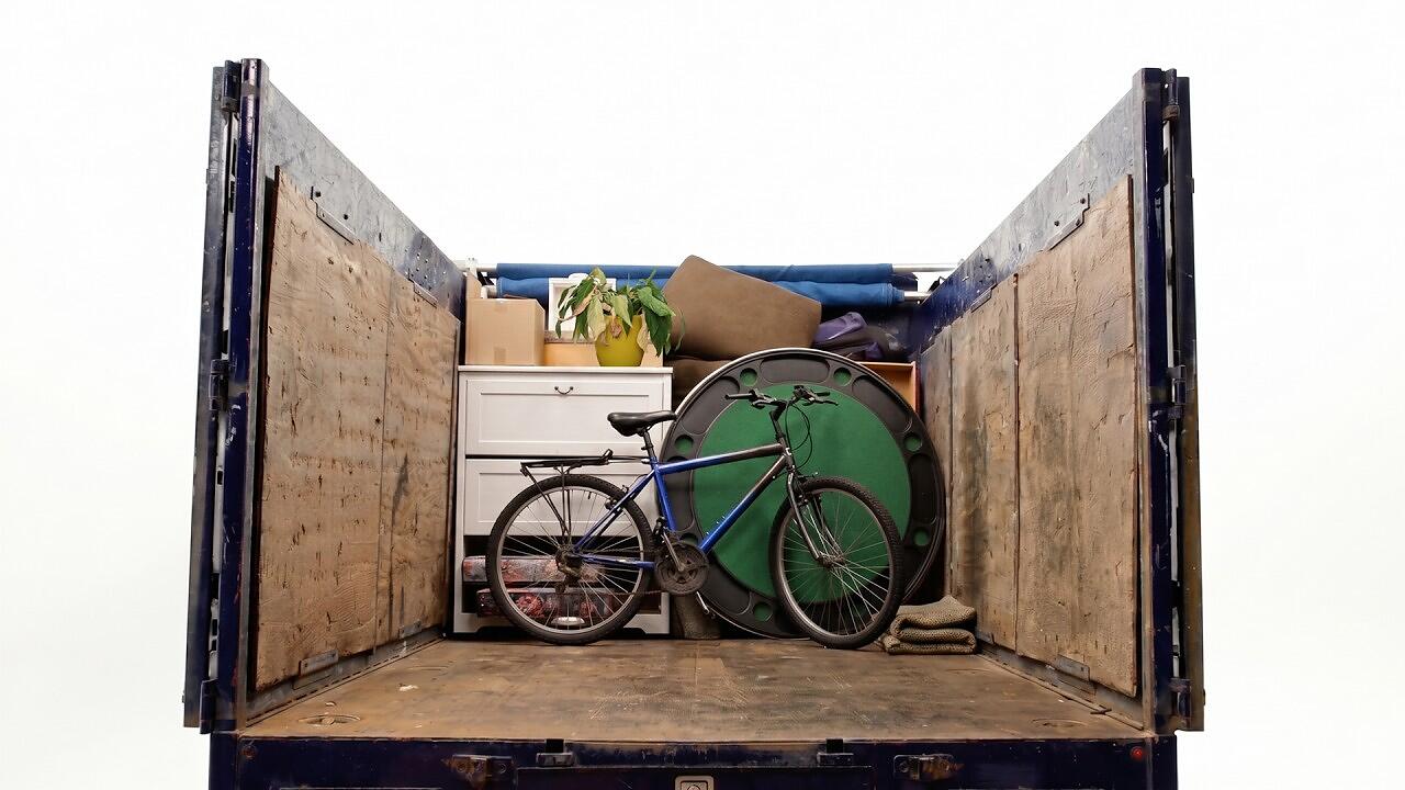 A presenter explaining junk removal volume pricing beside a truck